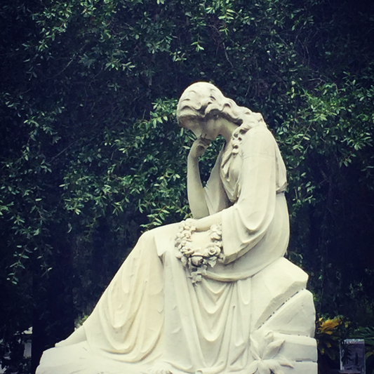 A statue of a woman holding a wreath of flowers, within Bonaventure cemetery in Savannah, Georgia, USA.