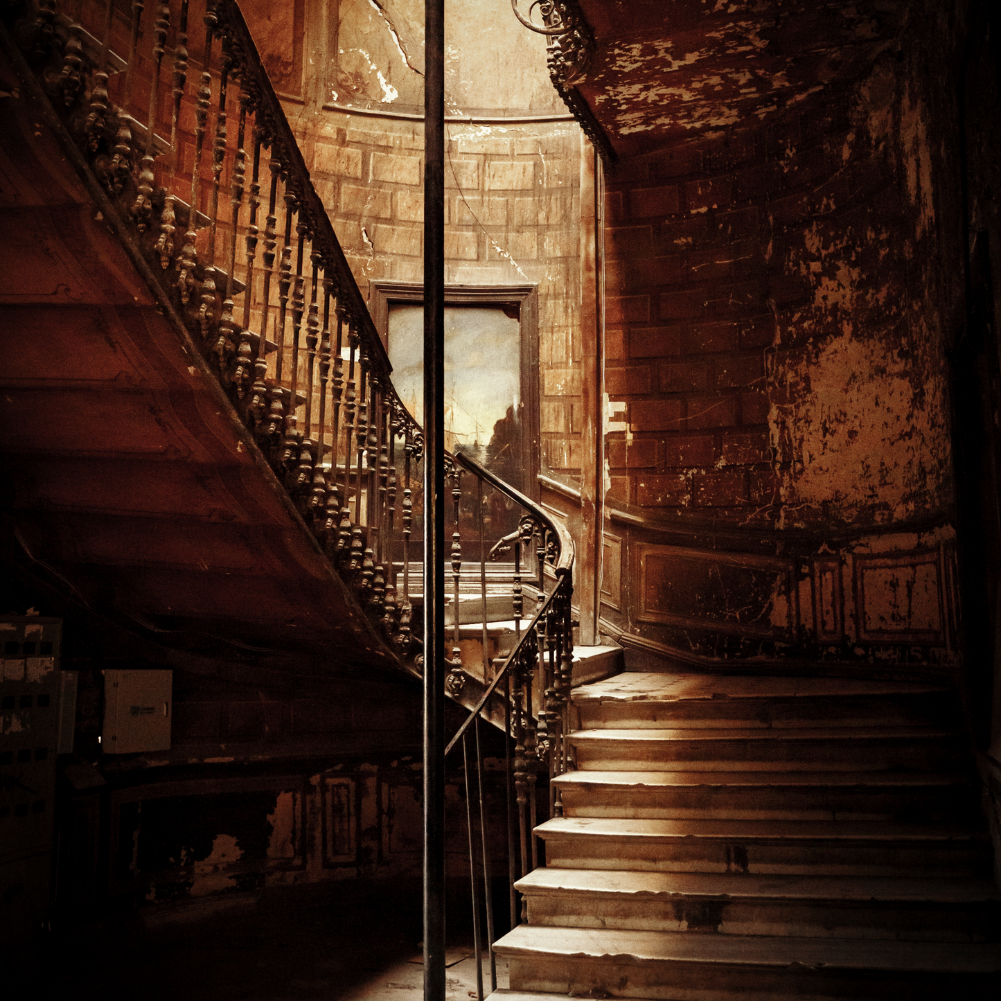 The staircase in an abandoned mansion, with peeling walls and ceiling.