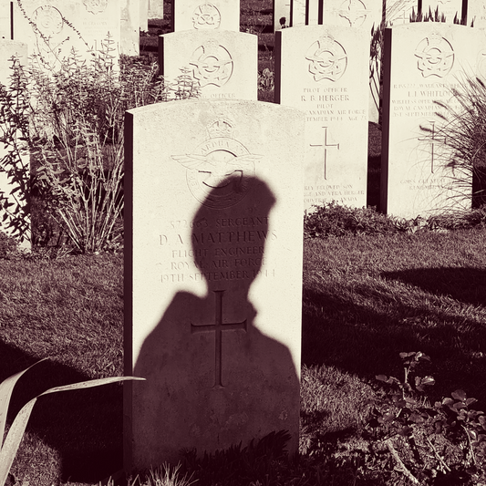A person's shadow on a headstone, in a cemetery.