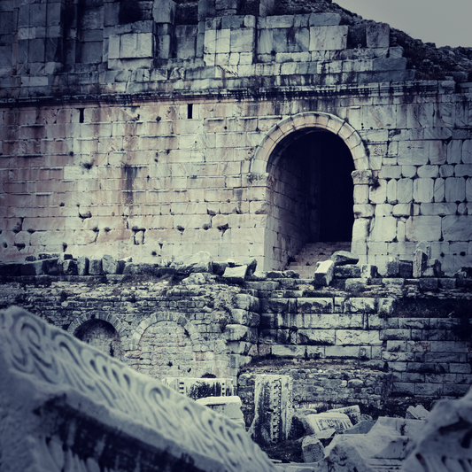 The crumbling ruins of a stone building, with a dark arched entrance.