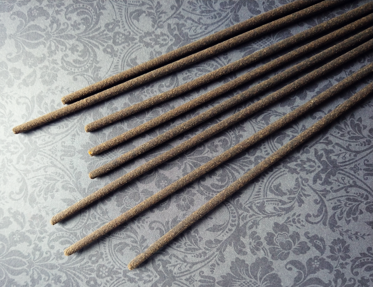 Eight (8) incense sticks on a black damask background.